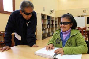 Foto: Señores de la tercera edad leyendo un libro en braille